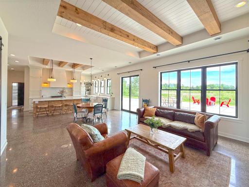 Reclaimed wood beams and beadboard ceiling details add character and architectural interest, while oversized windows frame picturesque country views