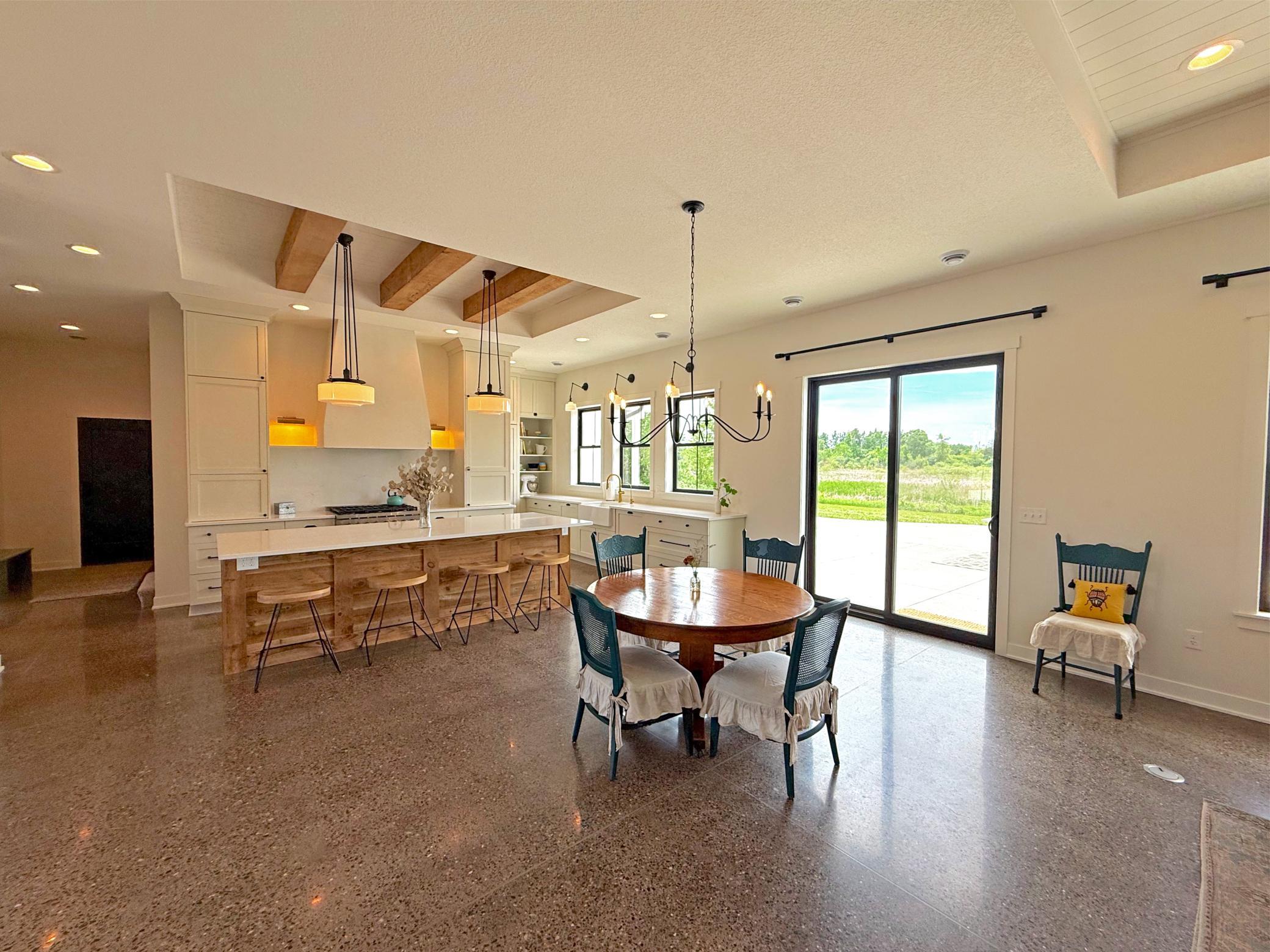 large center island wrapped in reclaimed wood provides ample seating and workspace, while expansive windows and a wall of glass fill the space with natural light.