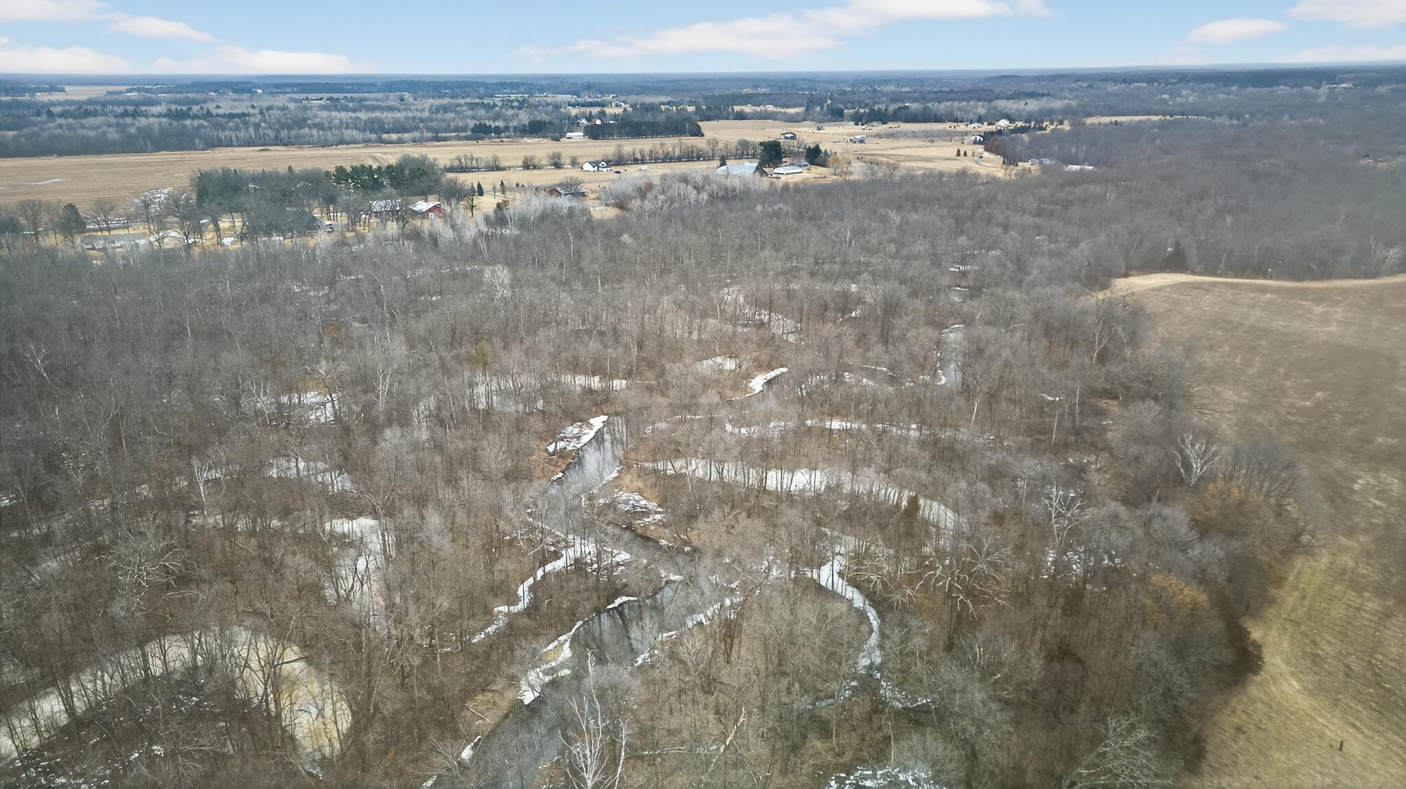 Bird’s-eye view of the property featuring open farmland, wooded edges, and the natural beauty of the Sunrise River. Total of 3 - 20-acre parcels available.