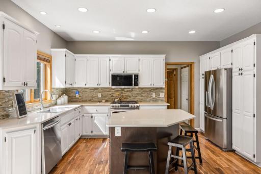 Spacious kitchen with quartz countertops, tile backsplash, gas stove, tons of storage.