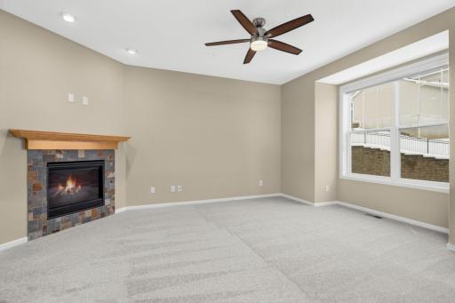 Bright and welcoming living room featuring a cozy gas-burning fireplace and neutral finishes. Nicely sized coat closet at the top of the stairs and a 1/2 bathroom.