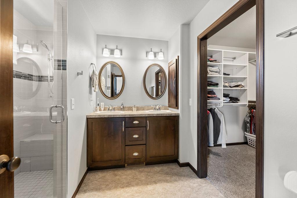 Primary bathroom: double sinks, glass enclosed tile shower, WIC