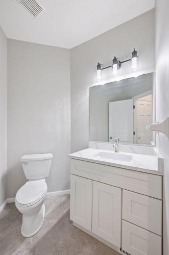 Main floor powder room features new vanity, quartz countertop and light
