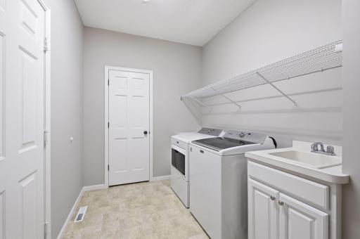 Main floor laundry room off the garage also features a large pantry or storage closet