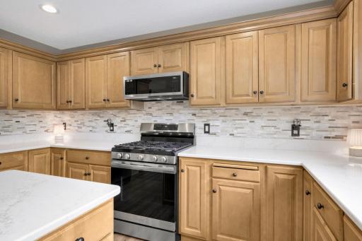 Updated Kitchen featuring Quartz countertops, tile backsplash, Gas Range, and plenty of workspace.