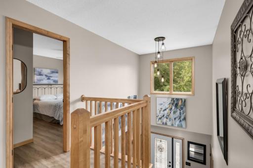 Open Upper-Level hallway overlooking the Foyer with abundant natural light and updated flooring.