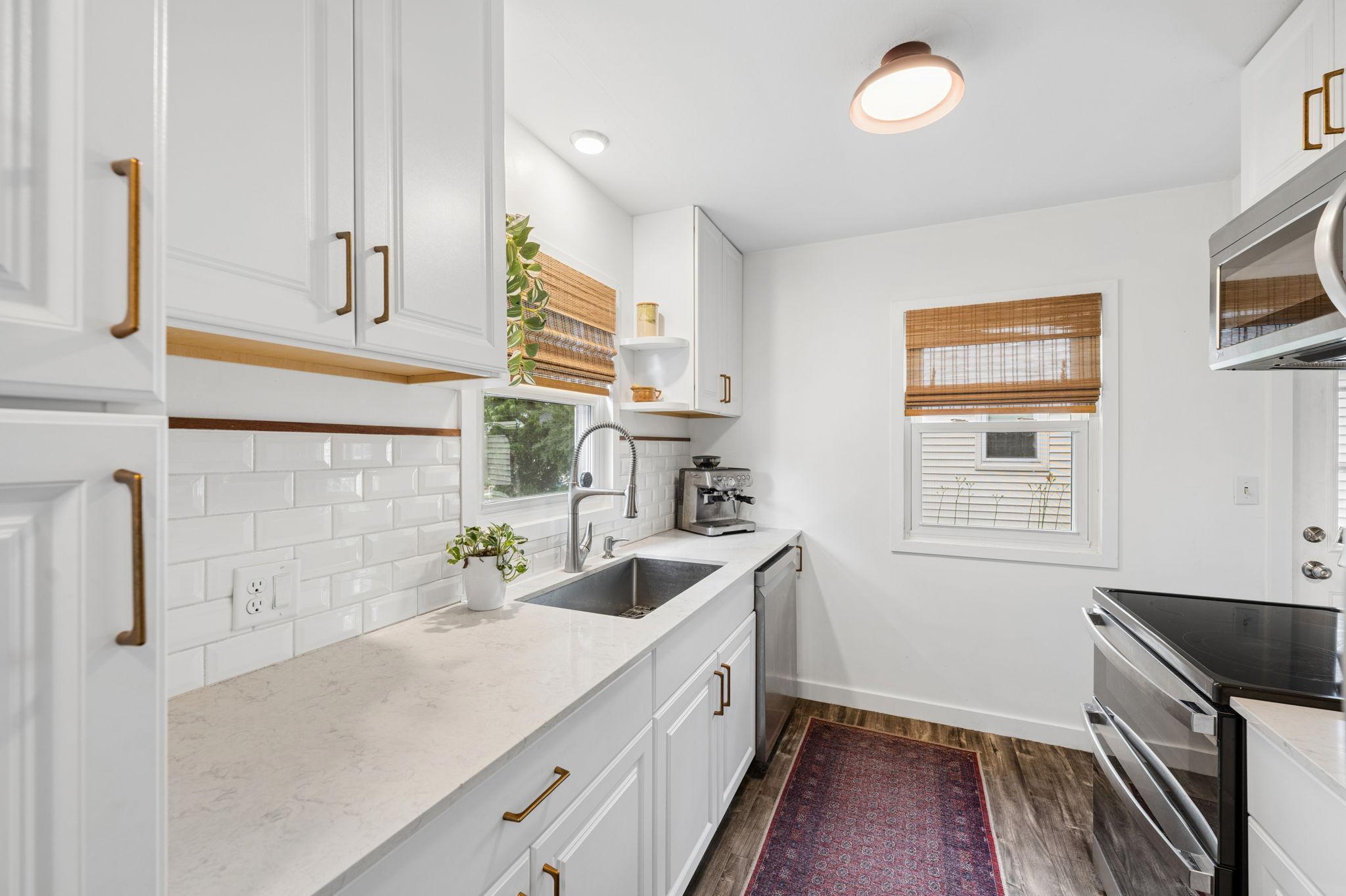 Updated kitchen with new cabinetry, classic tile backsplash, stone countertops, contemporary pulls and stainless steel appliances including a new oven (2025).