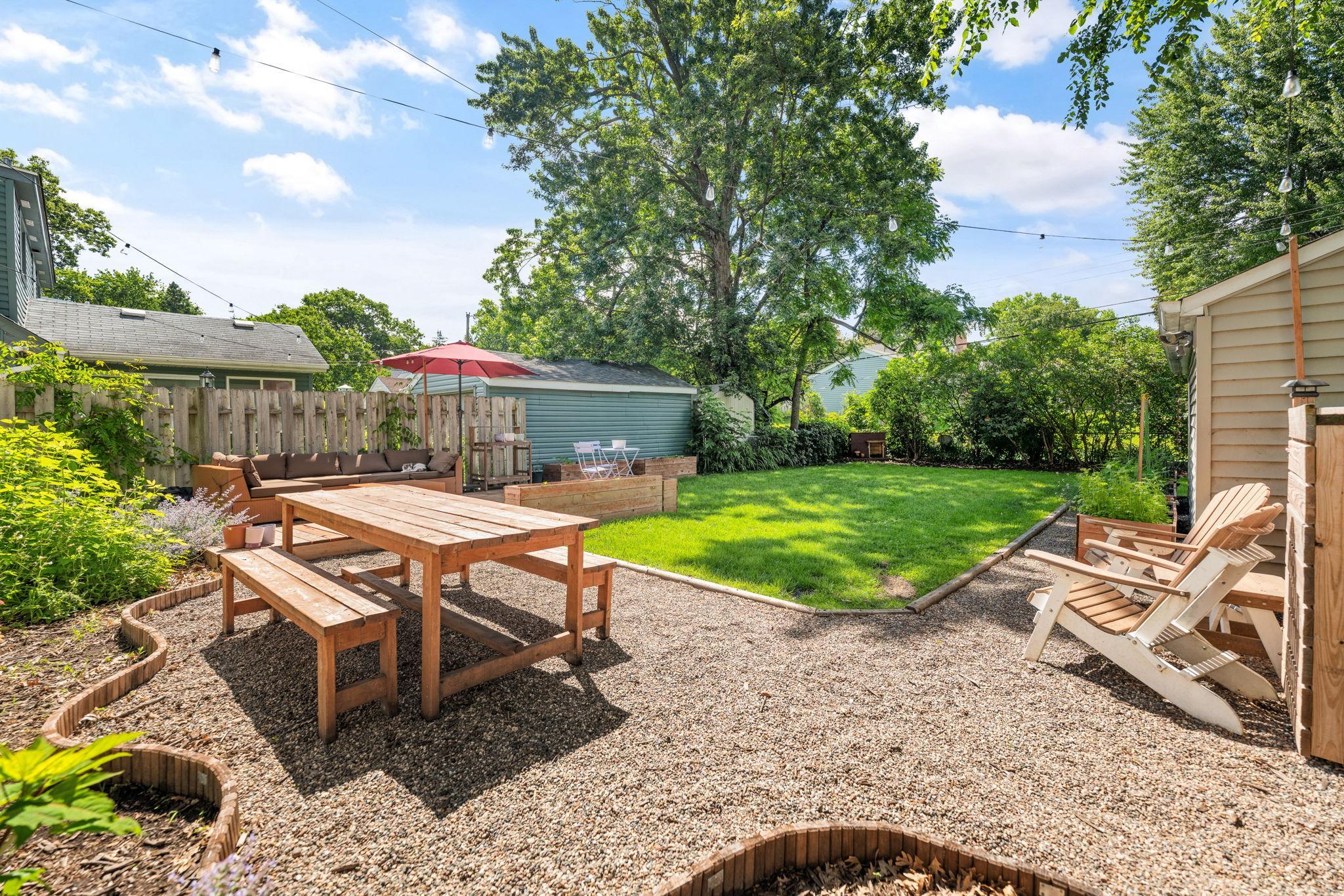 The fully fenced backyard is a gardener's dream: a pollinator garden, raised vegetable beds, a deck and gravel patio, a dog house, and a row of lilacs that bloom along the back of the lot every spring.