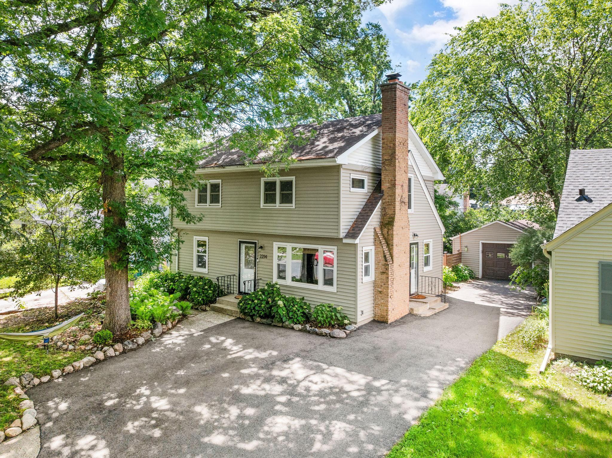 Out front, a shade garden filled with Annabelle hydrangeas sits beneath two mature oaks — perfectly spaced for a summer hammock. The garage adds storage and tool organization, and the driveway provides plenty of parking for all the guests you'll host