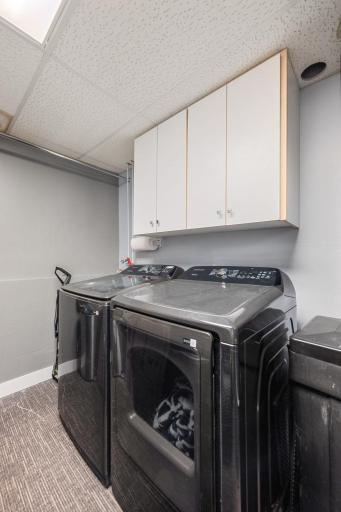 Clean, bright lower level laundry room with space for a min-fridge.