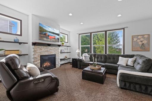 Spacious family room with a stone surround gas fireplace, large picture windows, and views of the backyard.