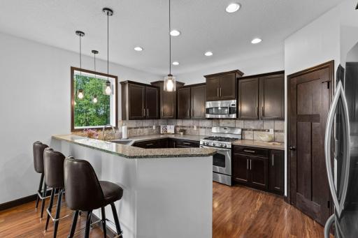 Beautiful kitchen featuring stainless steel appliances, center island with seating, abundant cabinetry, tile backsplash, and a convenient corner pantry.