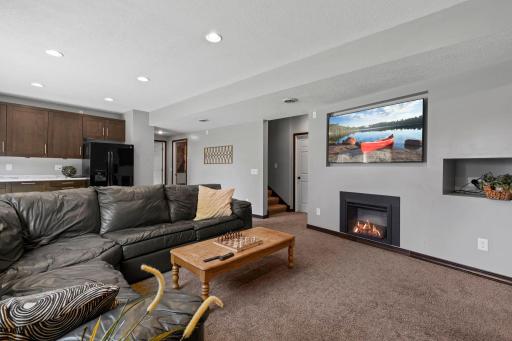 Expansive walkout lower level family room featuring a gas fireplace, built in bar area, and flexible space for entertaining, movie nights, or game day gatherings.