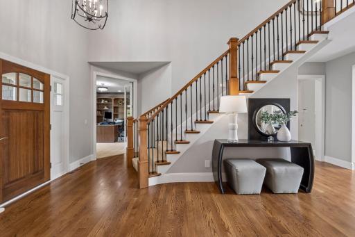 Front entry view of wood custom door into the main level office and main level primary to the right. Stunning curved staircase with rod iron spindles also adds to the elevated look and feel to this stunning home.
