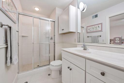 Ensuite bathroom with octagon tile flooring and milk glass tile surround shower accented by bread boarding on the walls.