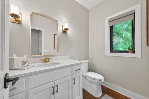 Main level powder room renovation features a custom vanity, black windows, brass fixtures, designer lighting, and premium finishes.