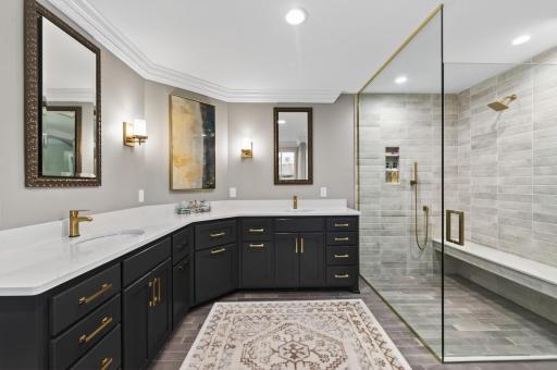 The spa-like ensuite bath offers a zero-entry tiled shower, oversized double sink vanity, toe-kick lighting, luxury finishes, & a private water closet.