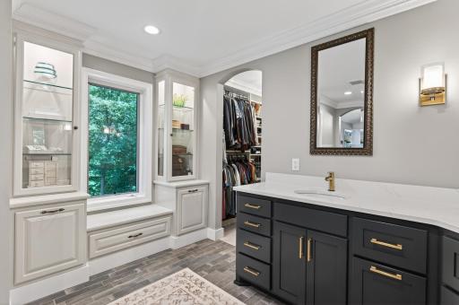 The owner's en suite boasts an extraordinary custom walk in closet with glass-front cabinetry, valet rods, shoe storage, fully extendable drawers, & double-row hanging space.