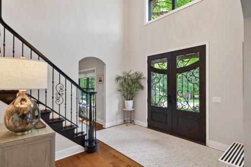 Light-filled entry welcomes guests with dramatic ceiling heights, elegant staircase, updated lighting, and refined architectural details throughout.