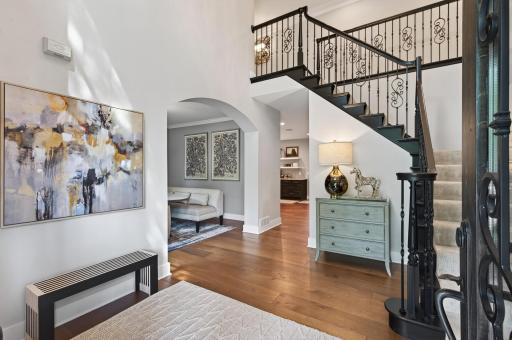 Impressive two-story foyer showcases soaring ceilings, custom millwork, designer lighting, and stunning real oak 10-inch plank flooring