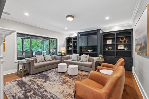 Warm and inviting family room showcases custom built-in cabinetry, integrated sound system, rich hardwood flooring, and expansive windows