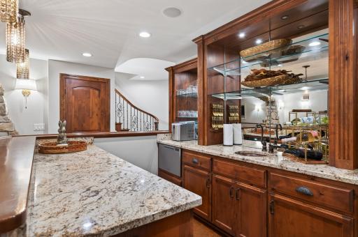 A private bartender's dream! Beautifully appointed full pub style bar with custom cabinetry, stone countertops, and professional-grade finishes to include (dishwasher, refrigerator, sink, custom bult in ice drawer, microwave).
