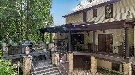 Expansive multi-level outdoor living with covered deck, warm stone pillars, and seamless indoor-outdoor flowâperfect for entertaining or relaxing in style.