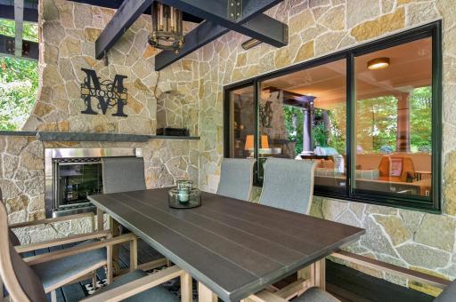 Sophisticated covered dining space anchored by stonework and designer lighting, seamlessly connected to the outdoor kitchenâideal for effortless al fresco entertaining.