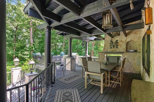 Multi-level, 900 square foot deck with black wrought iron railings features covered beamed outdoor dining space with infrared heaters, stone wall & gas fireplace, outdoor kitchen with refrigerator/freezer, gas grill, Big Green Egg & Aspen hot tub