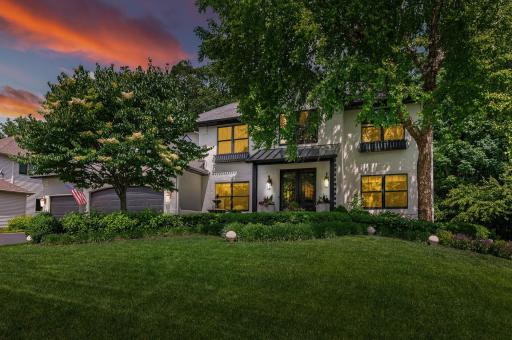 Freshly painted Parchment White stucco exterior, black-framed windows, black garage doors, custom front porch with metal hip roof, & professionally designed landscaping.