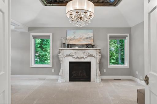 Exceptional owner's suite with a gas fireplace, sitting area and hidden drop-down television.