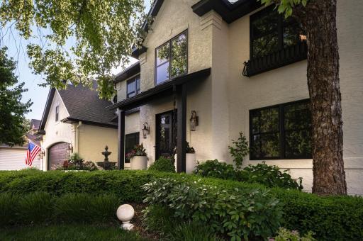 Front entry with covered porch and double doors, accented by exterior lighting and planters.