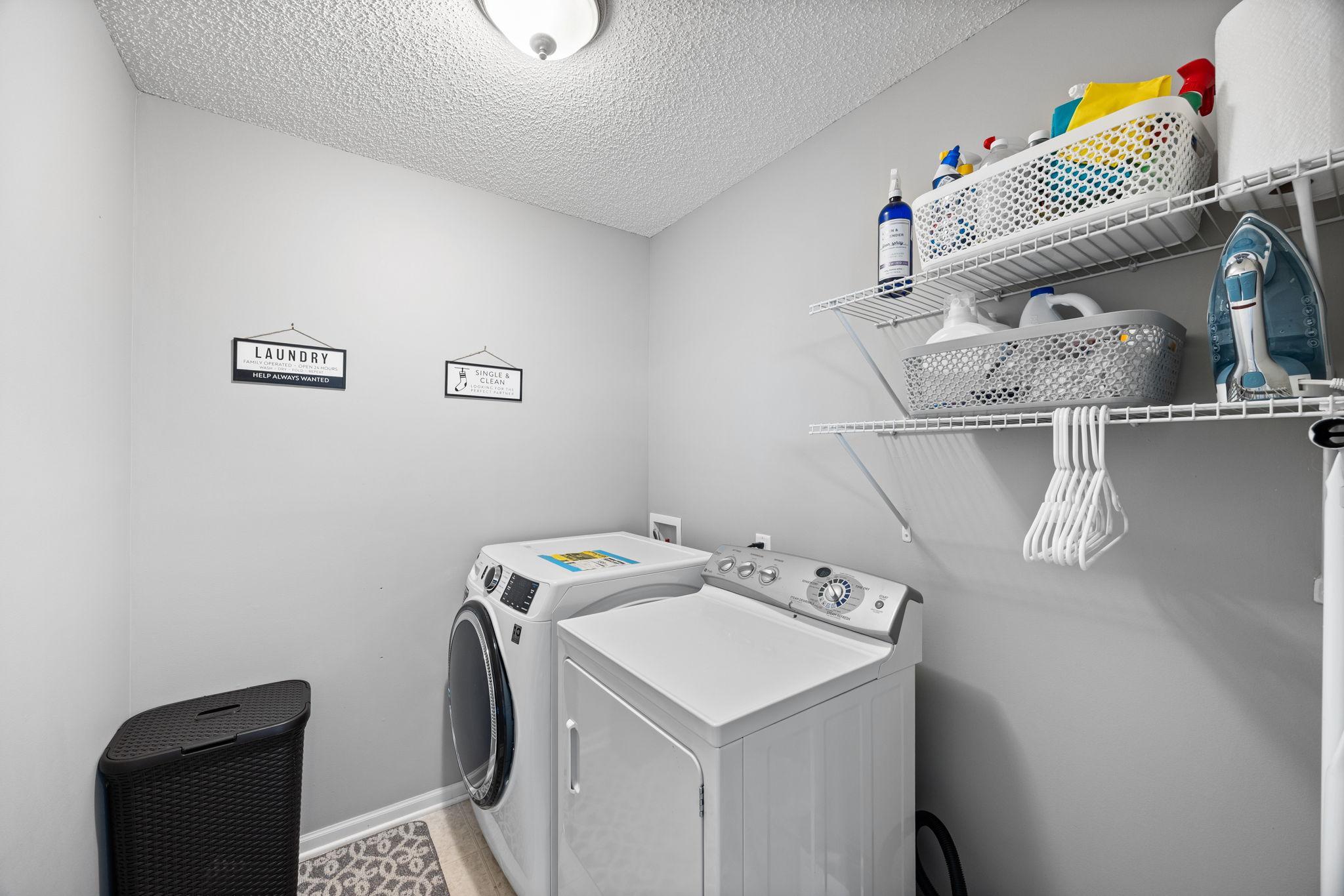 The upper-level laundry room, featuring a GE smart washer (2023), dryer, and built-in shelving, enhances daily routines.