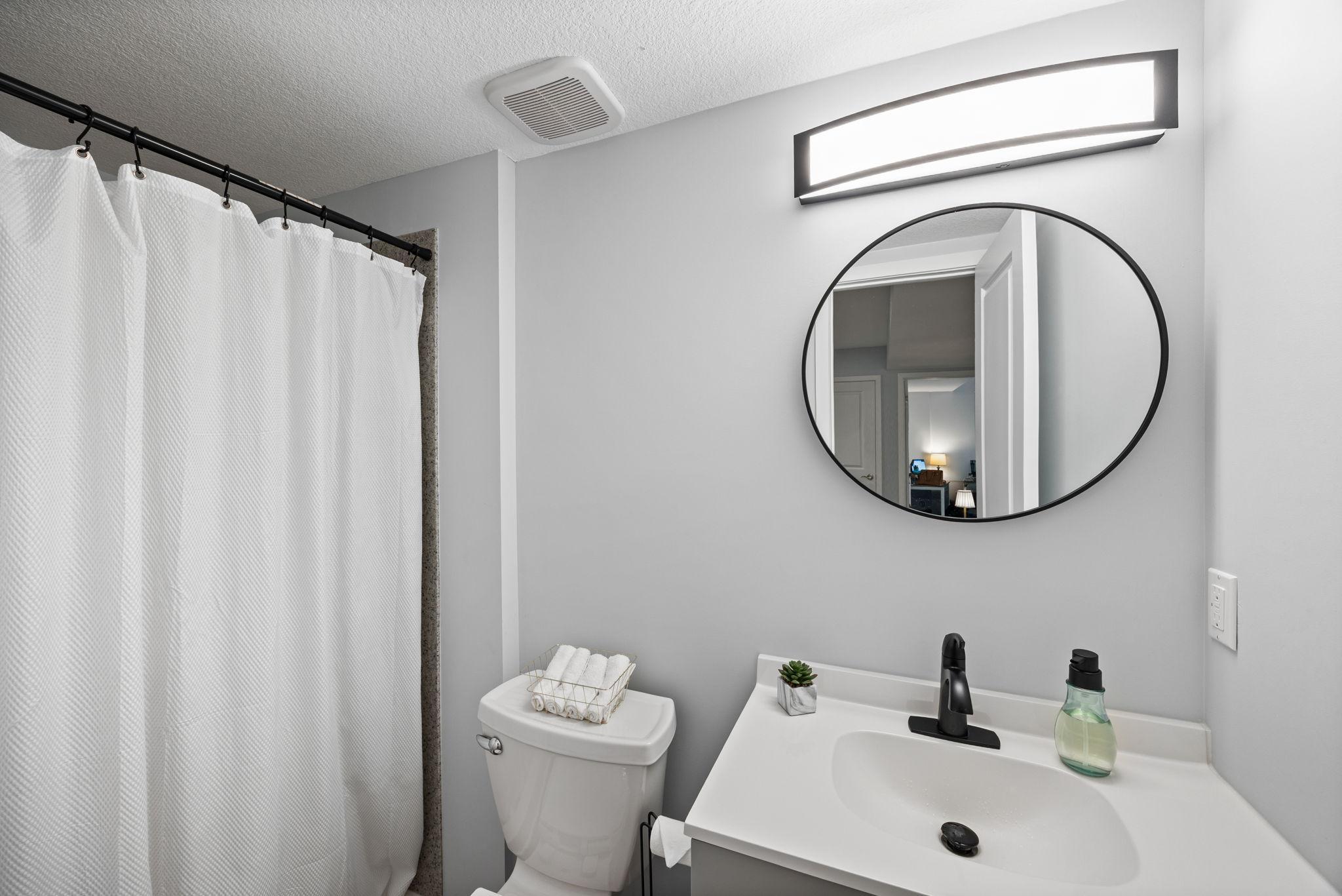 Nearby lower-level bathroom that includes a walk-in shower. Additional storage is thoughtfully tucked into a finished under-stair closet.