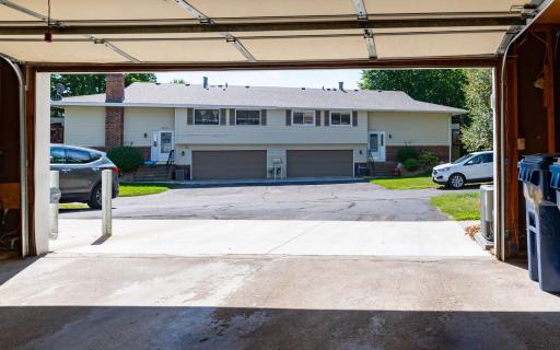 View from the inside of garage to the driveway, roadway and parking area.