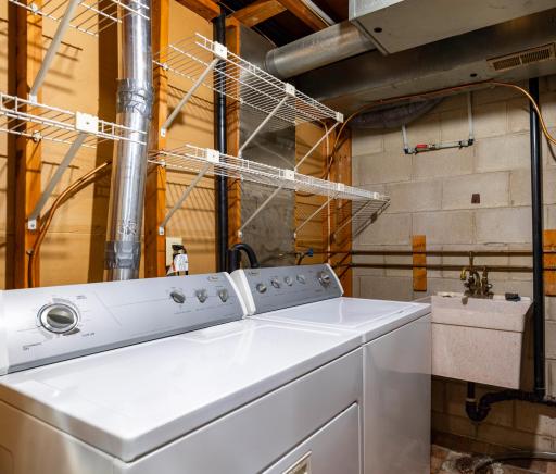 Lower level laundry and utility room with shelving and some storage.