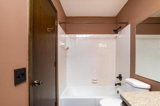 Main level full bath is accessible from main hallway as well as the primary bedroom.