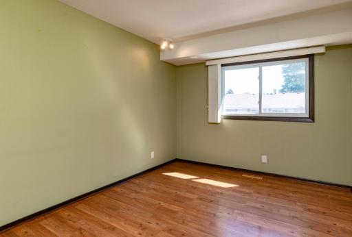 Main level primary bedroom featuring laminate flooring and plenty of afternoon sunlight.