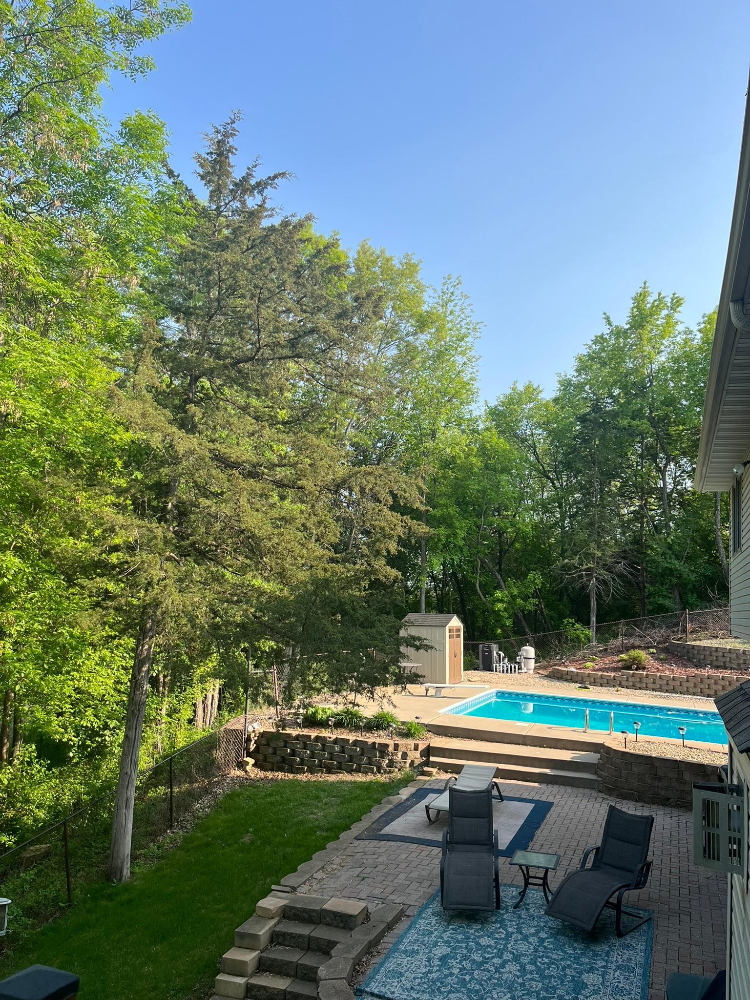 View from the deck looking towards the lower patio and pool area. This setting is wrapped in nature!
