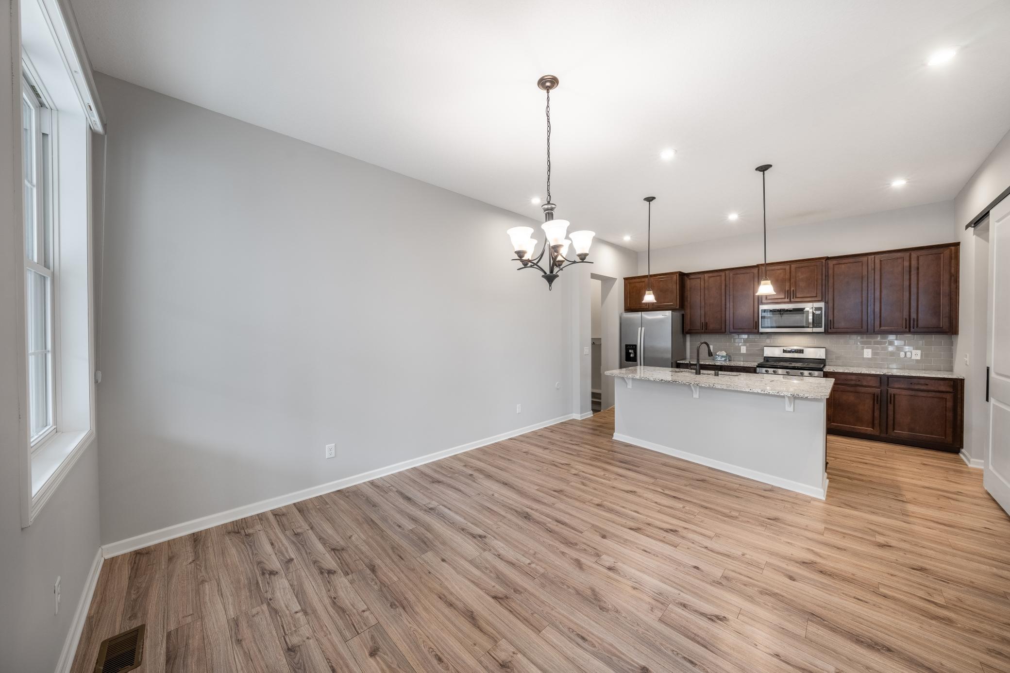 Large dining room with tall 10 ft. ceilings, beautiful durable wood look laminate flooring, and fresh paint throughout!