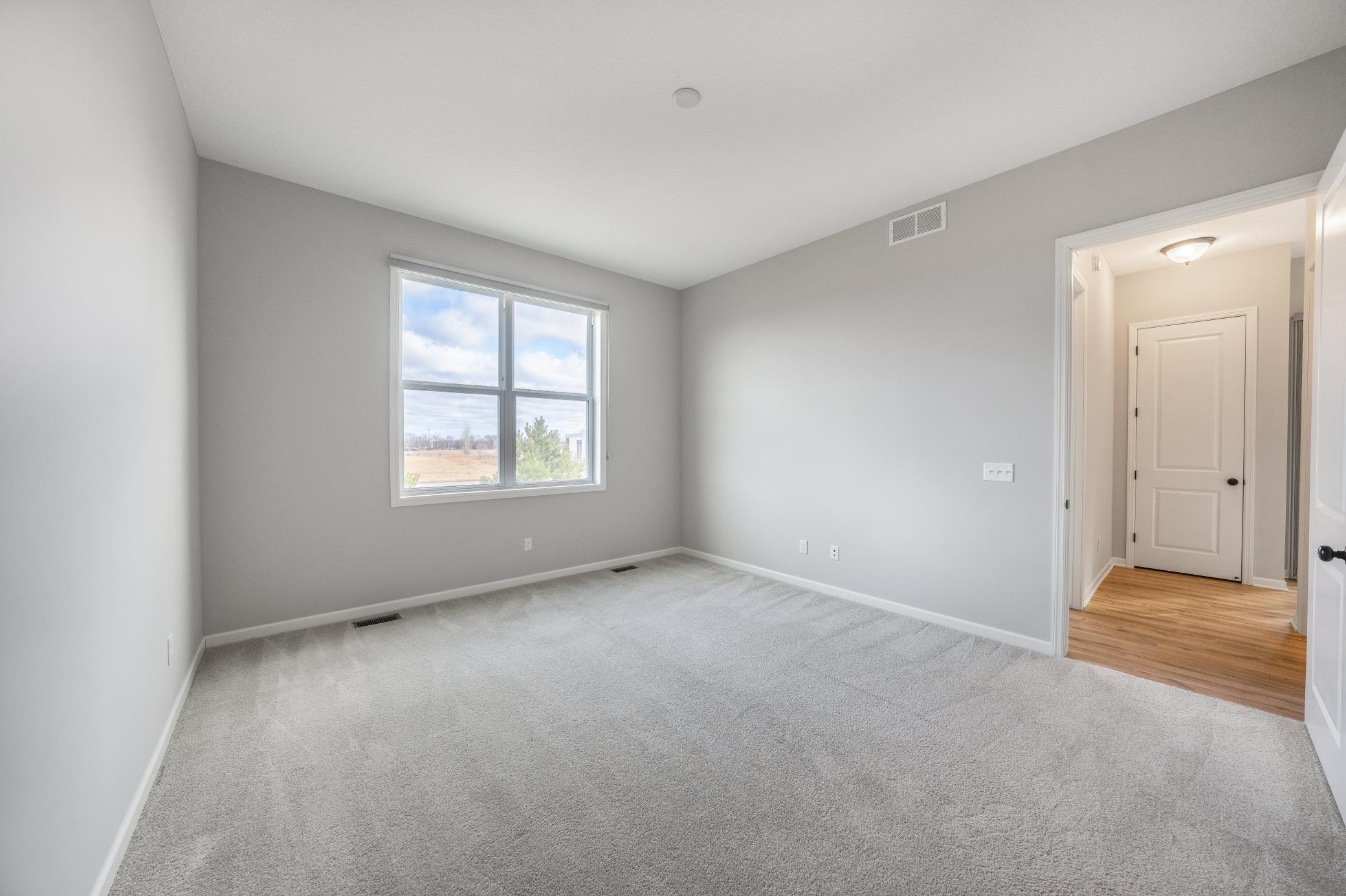 Spacious primary bedroom with attached walk in closet and ceramic tiled bathroom.