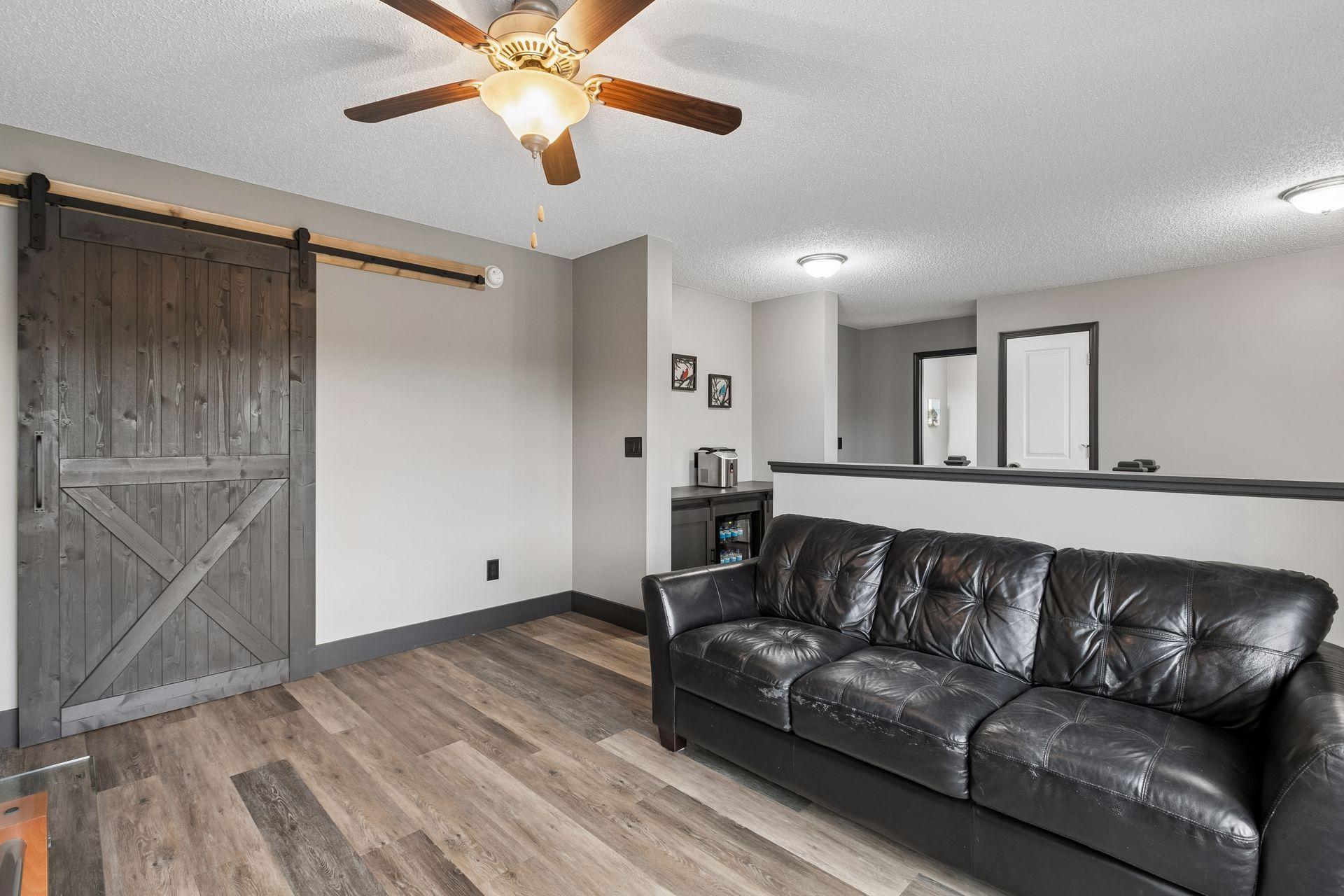 Upper level loft area with beverage fridge and area in background. Sliding barn door leads to large walk-in closet area.