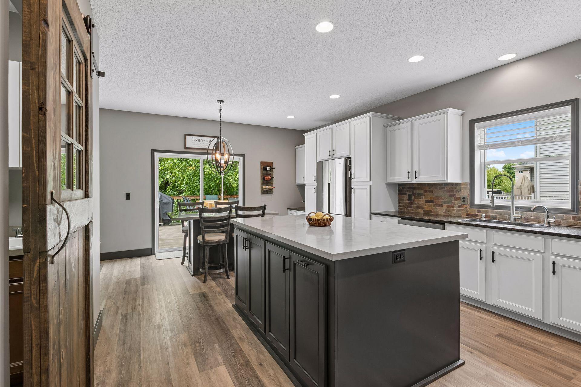 Gorgeous remodeled kitchen (2021) with two-toned painted and stained kitchen, center island and quartz countertops, new fixtures and sliding barn accent door. Bonus eat-in area with dry bar area, sliding patio doors to backyard deck.