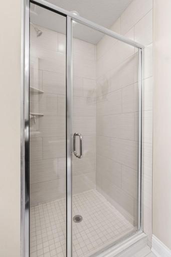 Vaulted Primary Suite w/ ensuite Bath featuring tiled shower, granite counters, 12x24 tile + walk-in closet.