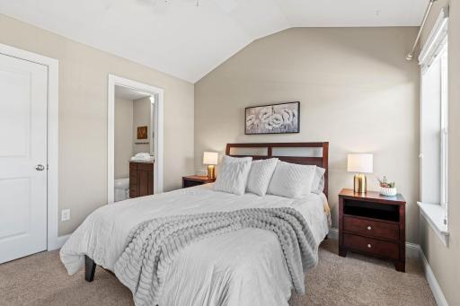 Vaulted Primary Suite w/ ensuite Bath featuring tiled shower, granite counters, 12x24 tile + walk-in closet.