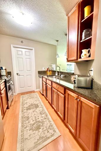 Galley-style kitchen with granite countertops, stainless steel appliances and an in-sink disposal. Behind the door is the laundry and utility area.