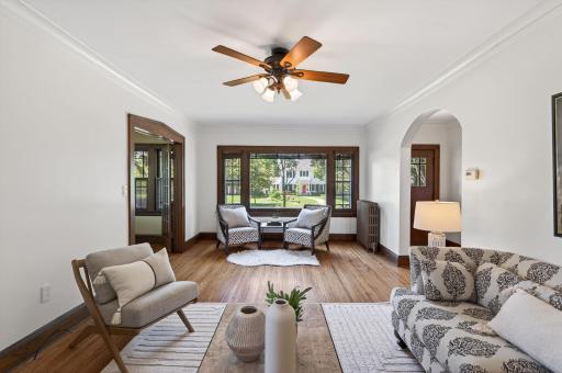 Sun-filled living room featuring original character, hardwood floors, and graceful archways.