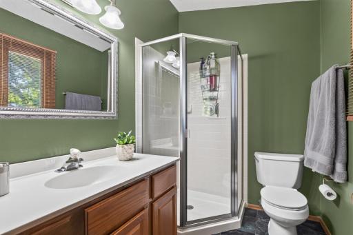 Primary bath, vaulted ceiling, window for natural light, tile flooring.
