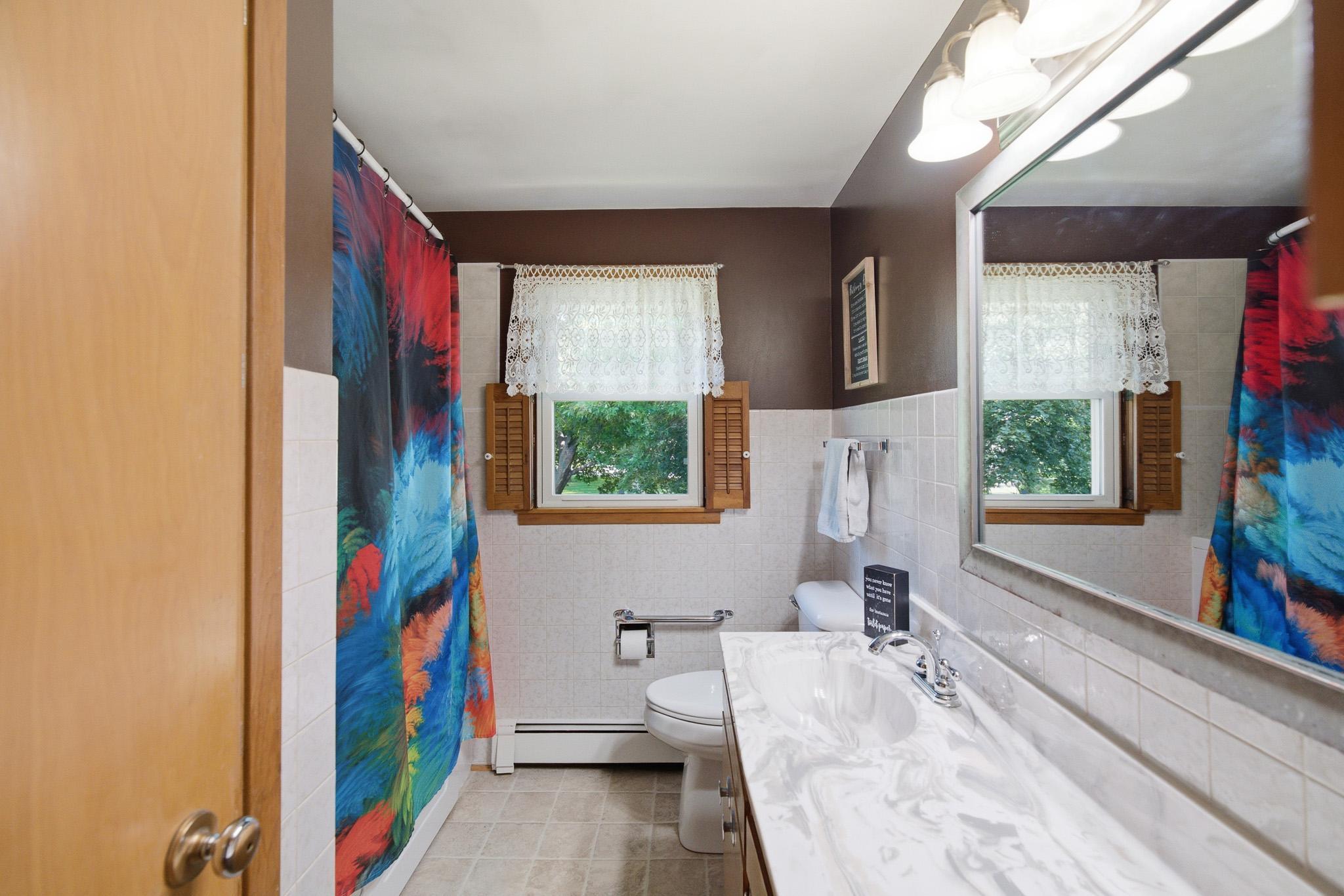 Bright full bathroom featuring a spacious vanity, generous counter space and abundant natural light.