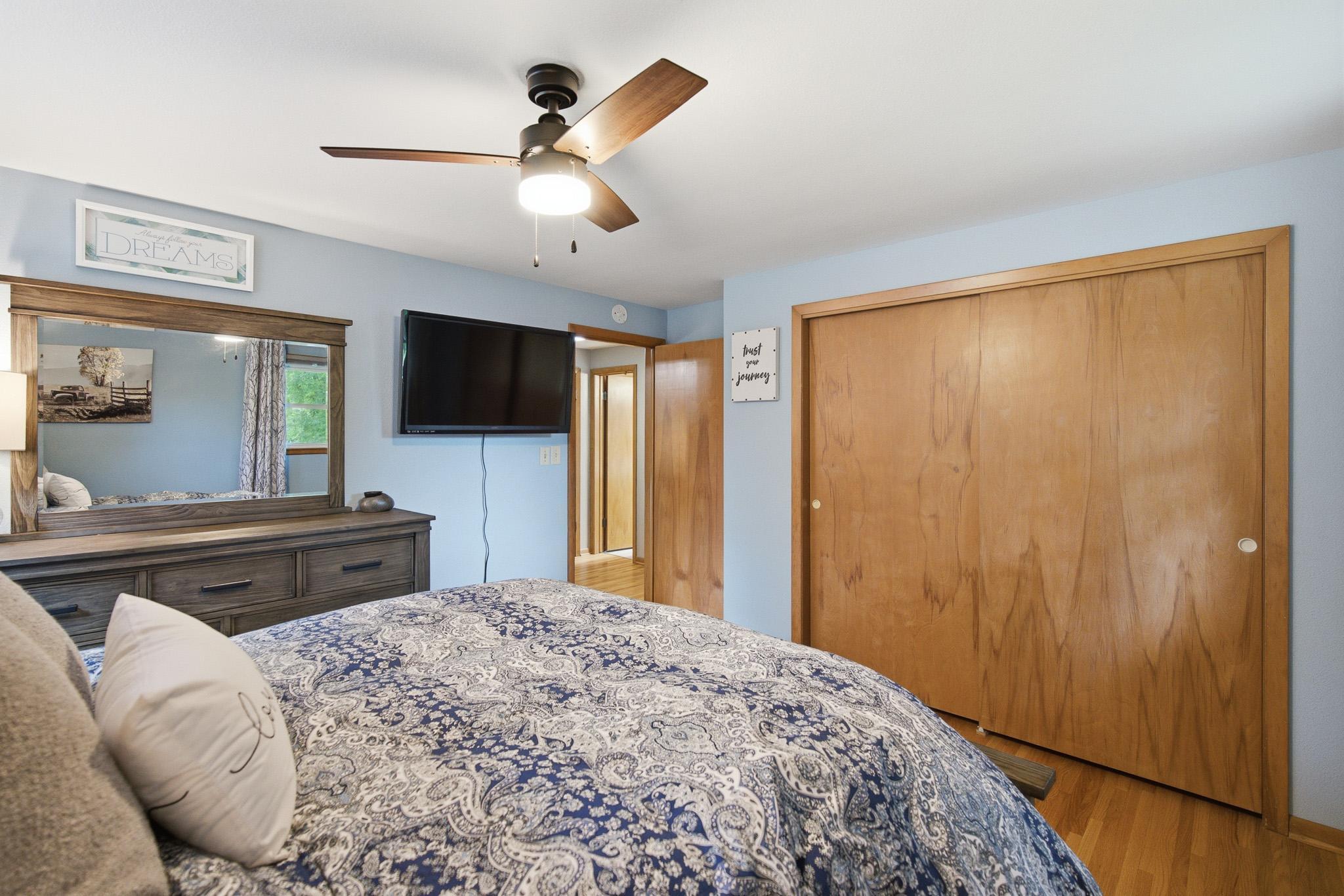 Comfortable bedroom with hardwood floors, ceiling fan, and plenty of natural light.